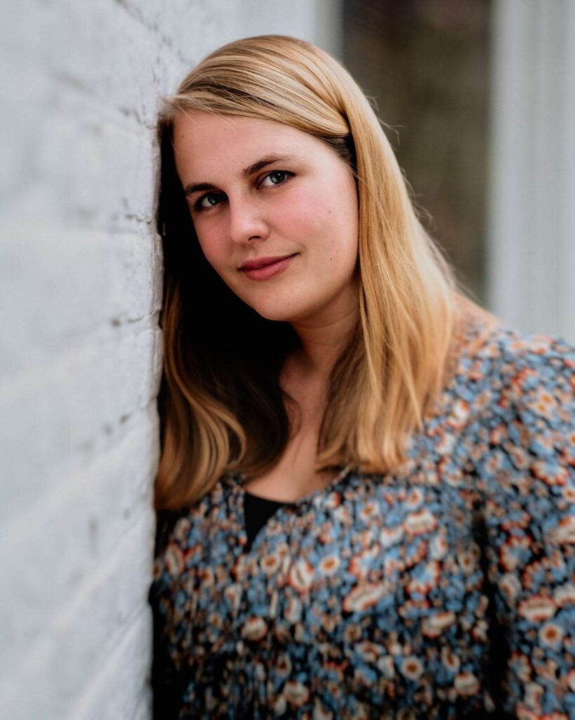 Girl leaning against a white wall.