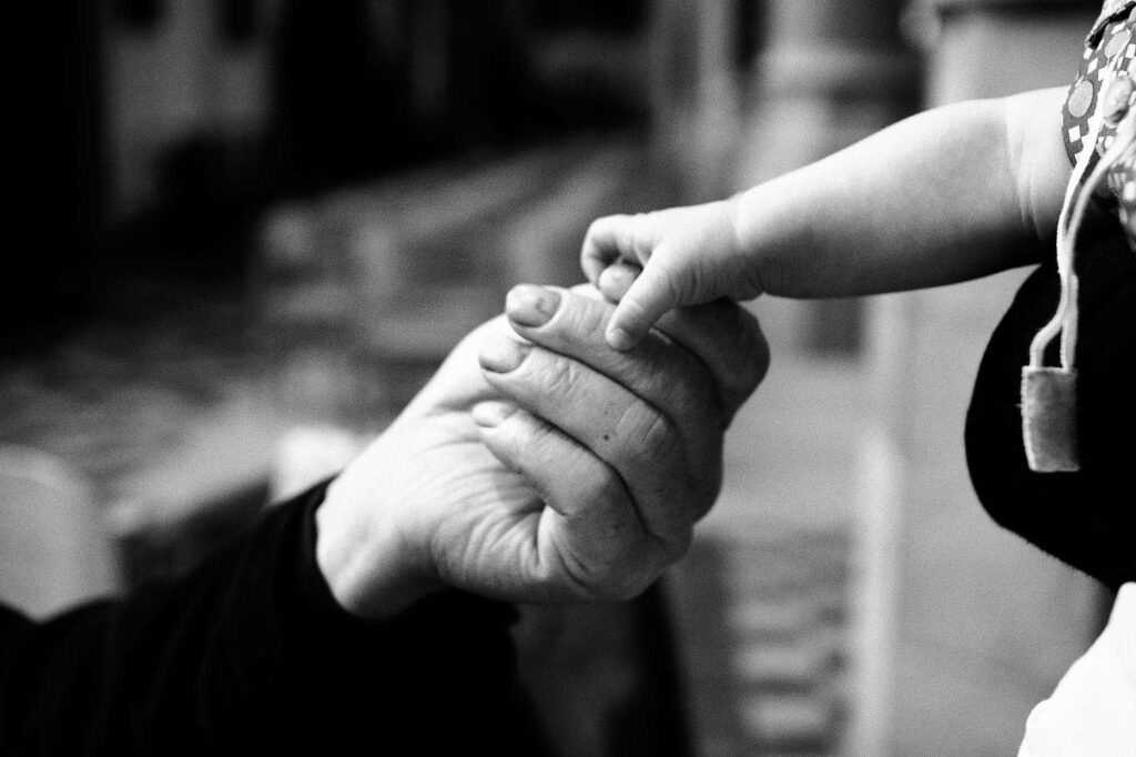 Hand of a grandfather holding granson's fingers.