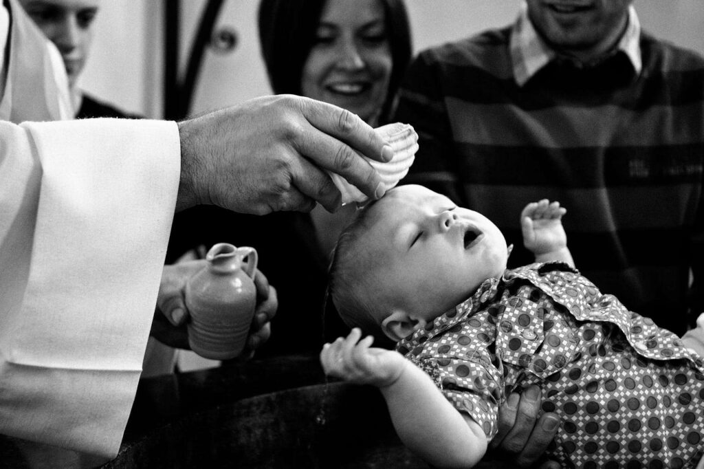 Picture of a young boy getting baptised by a priest.
