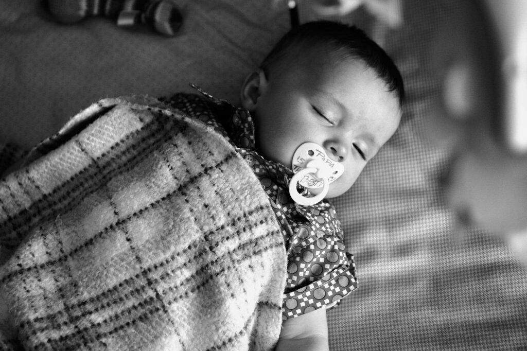 Picture of young baby boy sleeping with a pacifier.