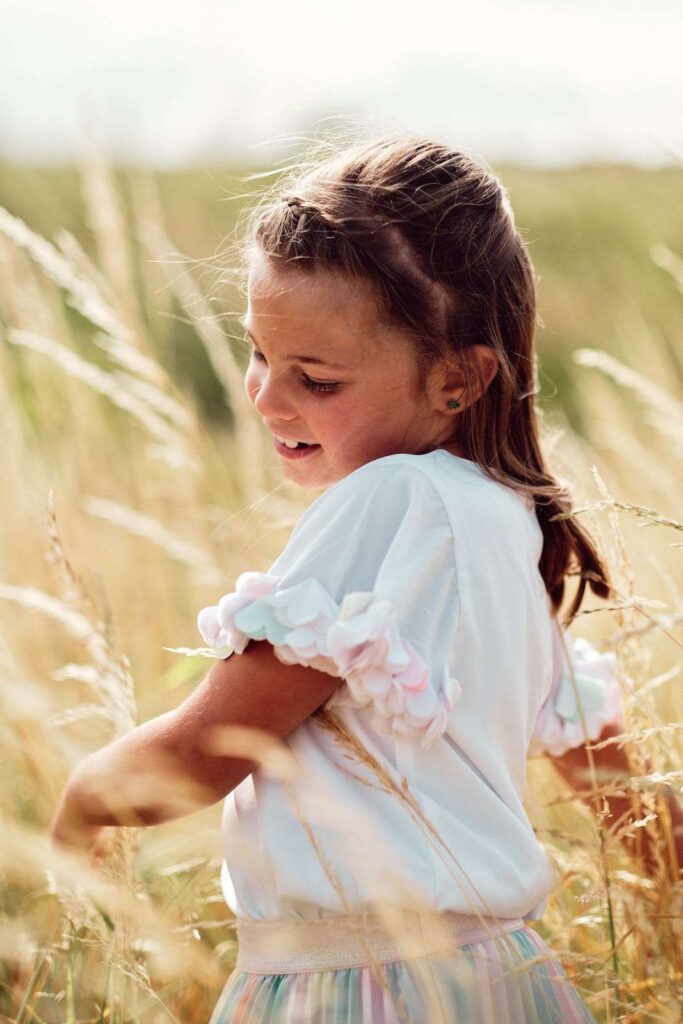 Portrait of a girl playing in between tall grass.