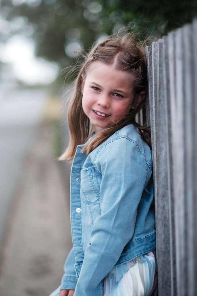 Portrait of girl looking sideways while leaning against a wall.