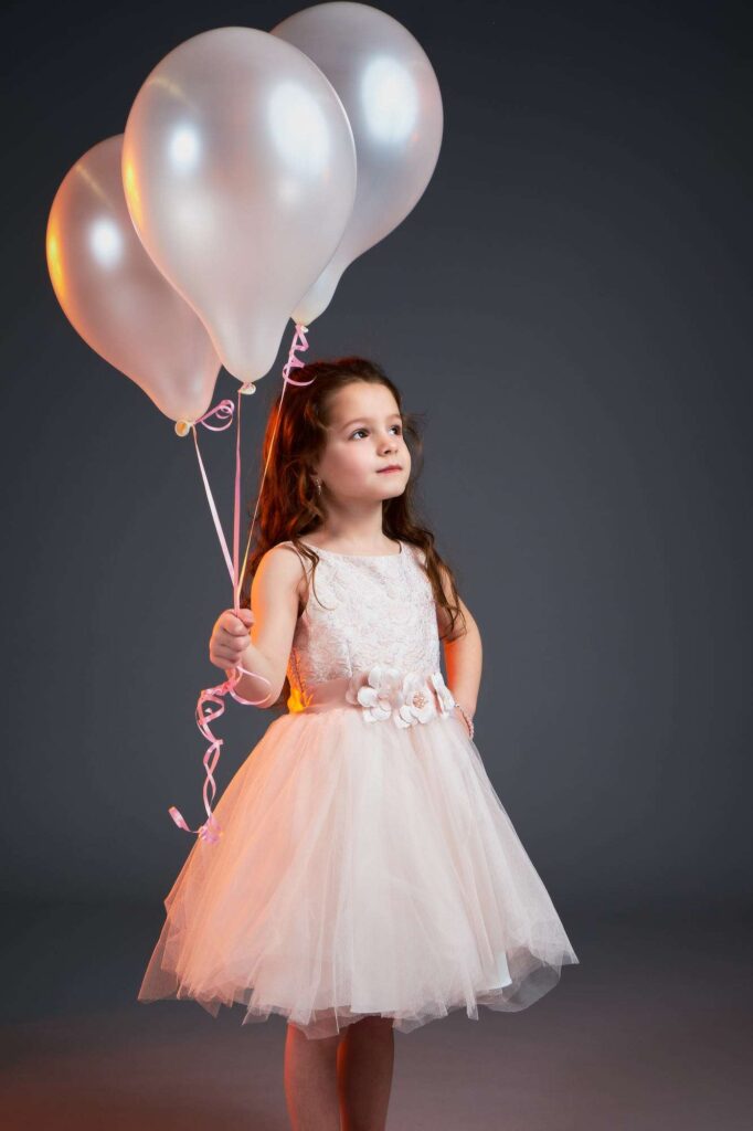 Girl posing with white balloons.