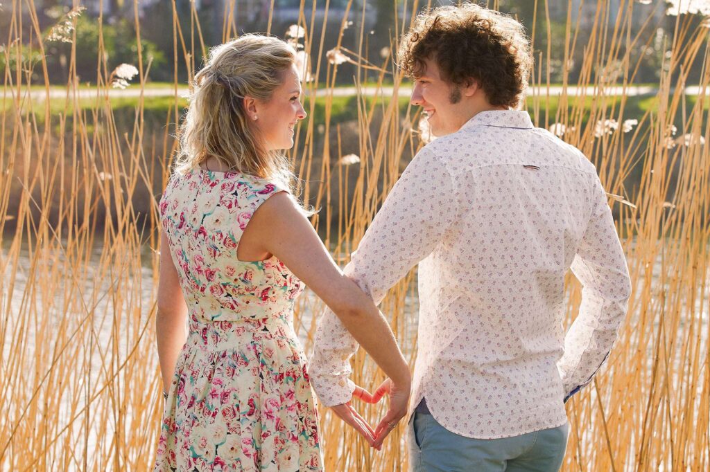 Photo of a couple posing with hands in a heart shape.
