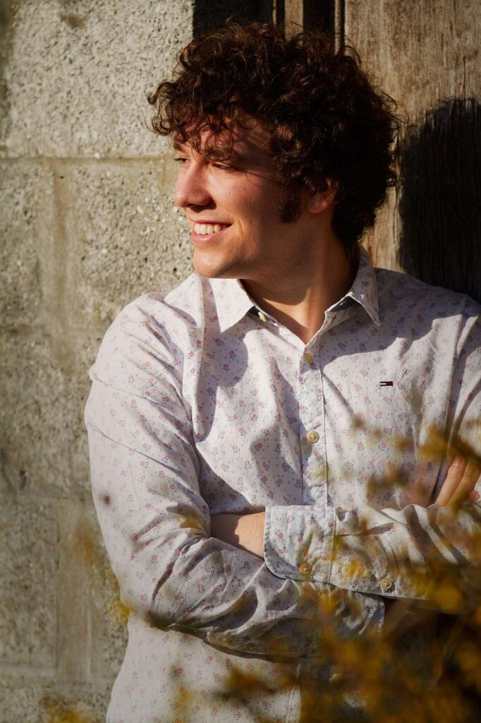 Man posing while leaning against a wall.
