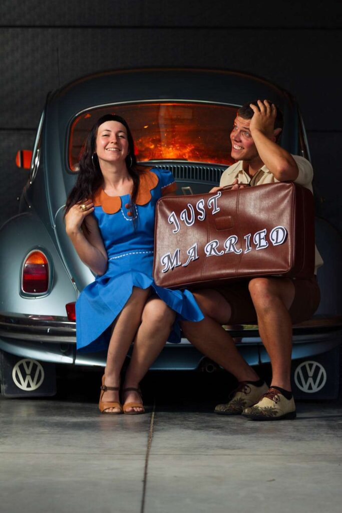 Man and woman in happy pose with a suitcase on their laps.